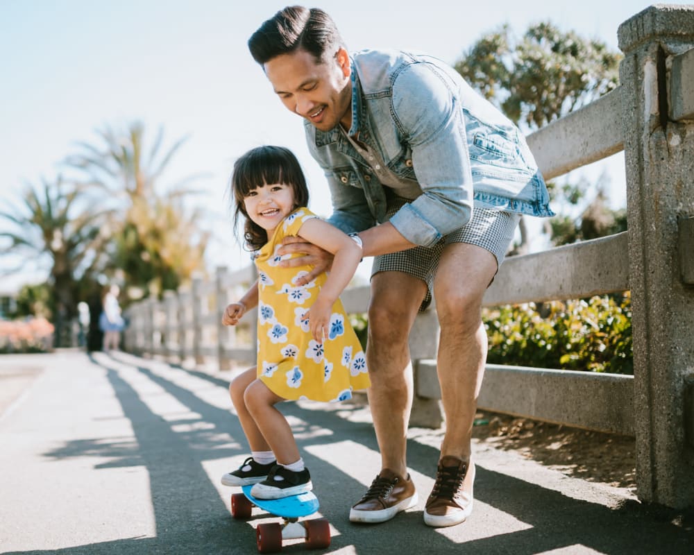 A father helping his daughter skateboard near Pomerado Terrace in San Diego, California
