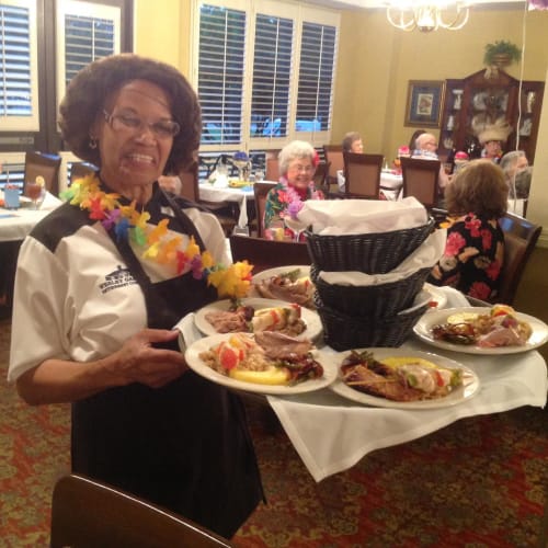 Server carrying a giant tray of food to a table of residents at Wesley Gardens in Montgomery, Alabama