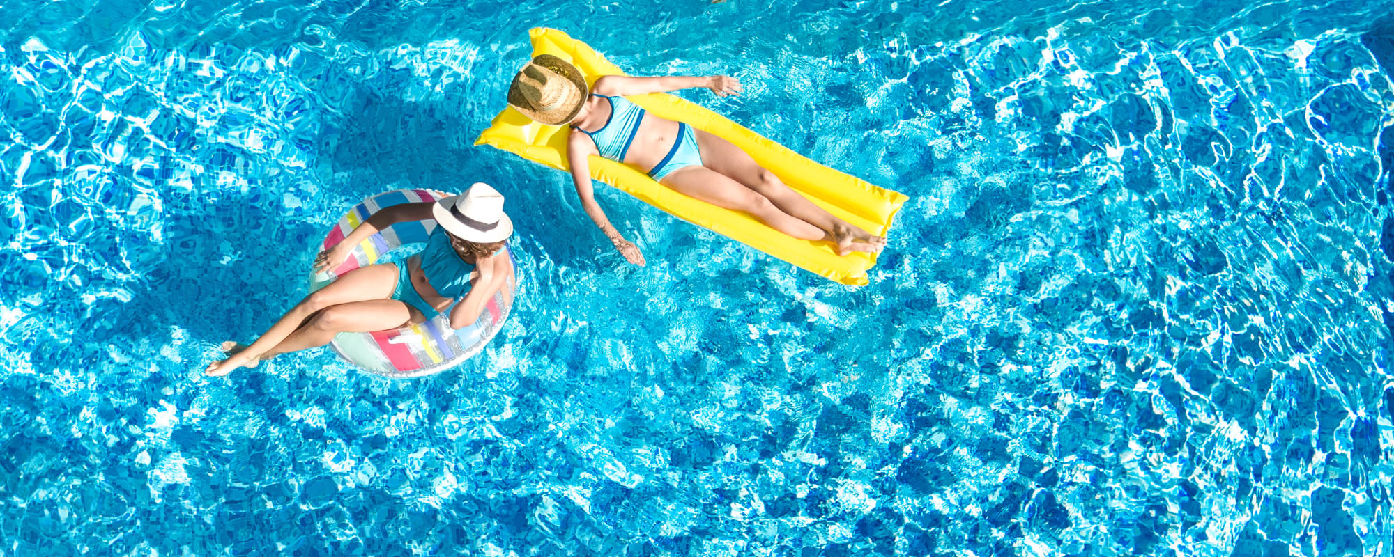 Residents relaxing on floats in a swimming pool at Desert View Terrace in Twentynine Palms, California