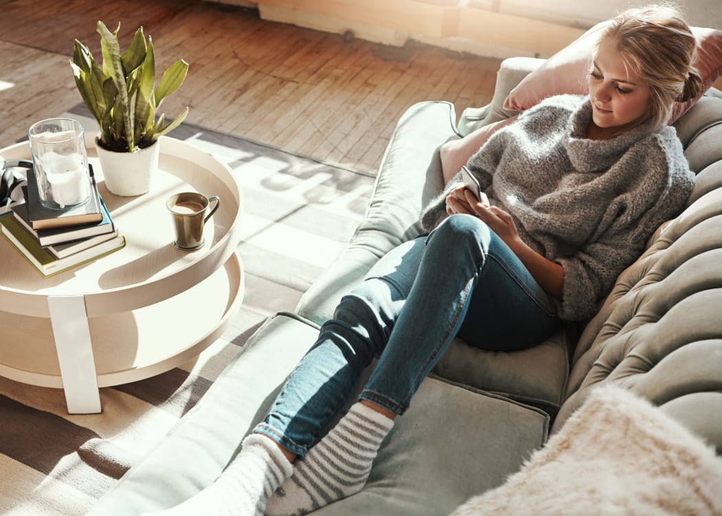 Resident relaxing on her couch at Cedartree Apartments in Santa Clara, California