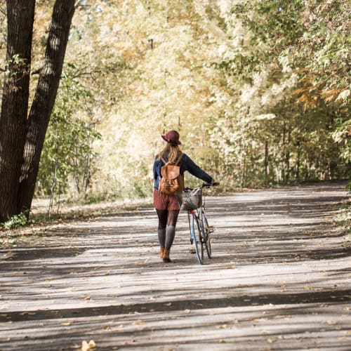 Resident walking her bike in a park near Cobble Creek Apartment Homes in Chico, California