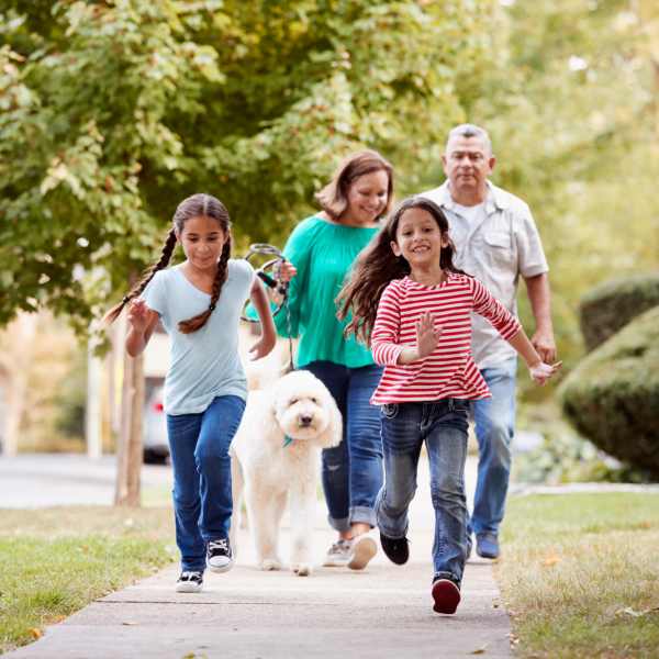 Family walking with dog on sidewalk near Valley Brook Townhomes in Rochester, New York