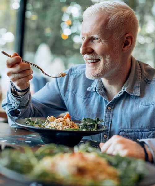 Resident enjoying his meal in a nearby restaurant at Athens Vista Senior Apartments in Los Angeles, California