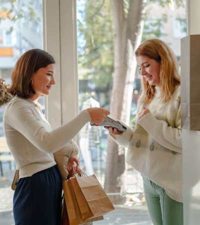 Two women exchanging items at a bright entrance, smiling and enjoying their time together at Dutch Village Apartments in Baltimore, Maryland 