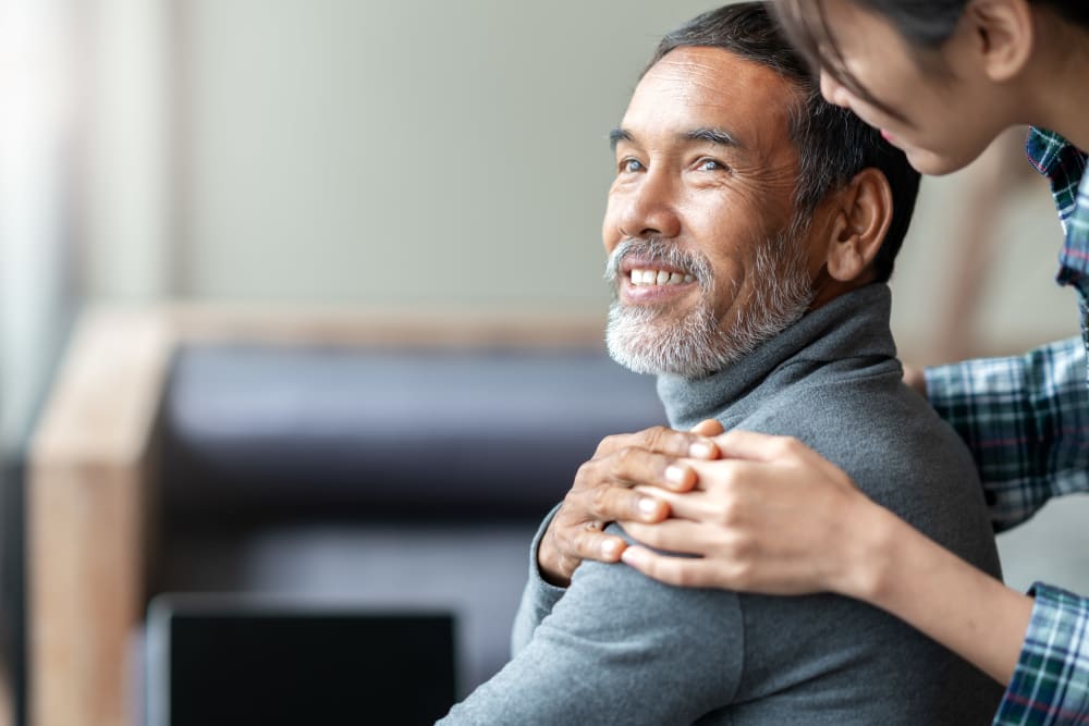 A senior resident with a supporting hand on his shoulder at Regency Palms Colton in Colton, California.