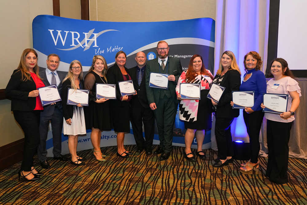 Employees at WRH Realty Services, Inc show off their awards in a group shot
