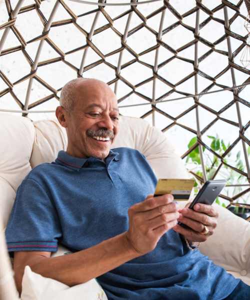 Man making online payment in his balcony at Athens Vista Senior Apartments in Los Angeles, California