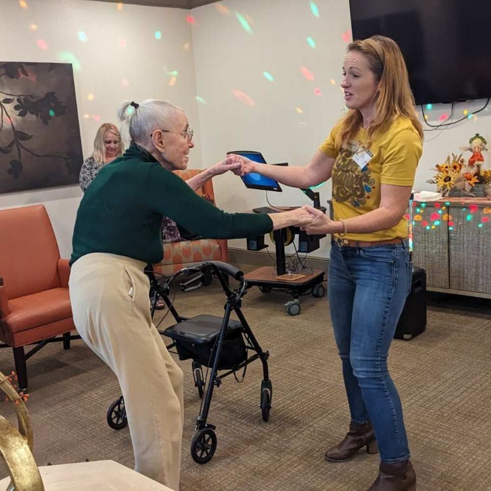 Resident dancing with a team member during a music and movement activity at The Landing at Shadow Creek Ranch in Pearland, Texas.