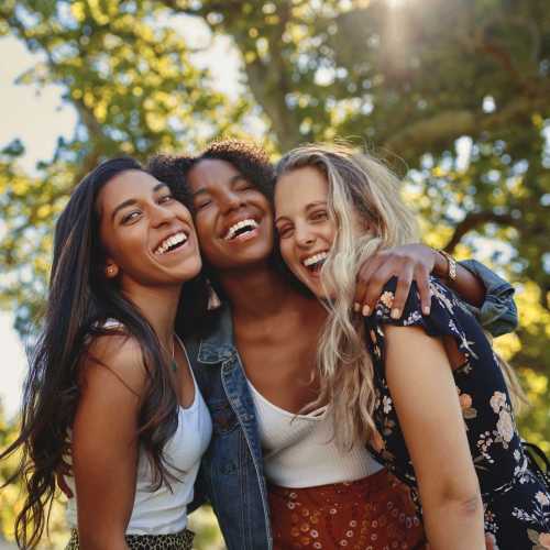Three women smiling together outdoors near Avia Lofts at Maple Road in Amherst, New York