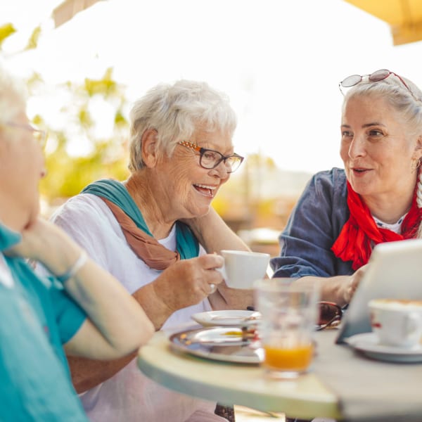 Resident friends dining outdoors at Pacifica Senior Living Hillsborough in Chino, California.