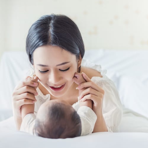 A mother playing with her kid in bed at Santa Margarita in Oceanside, California