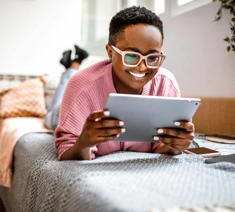 Student resident using a tablet phone on the bed at The Edge in Pensacola, Florida