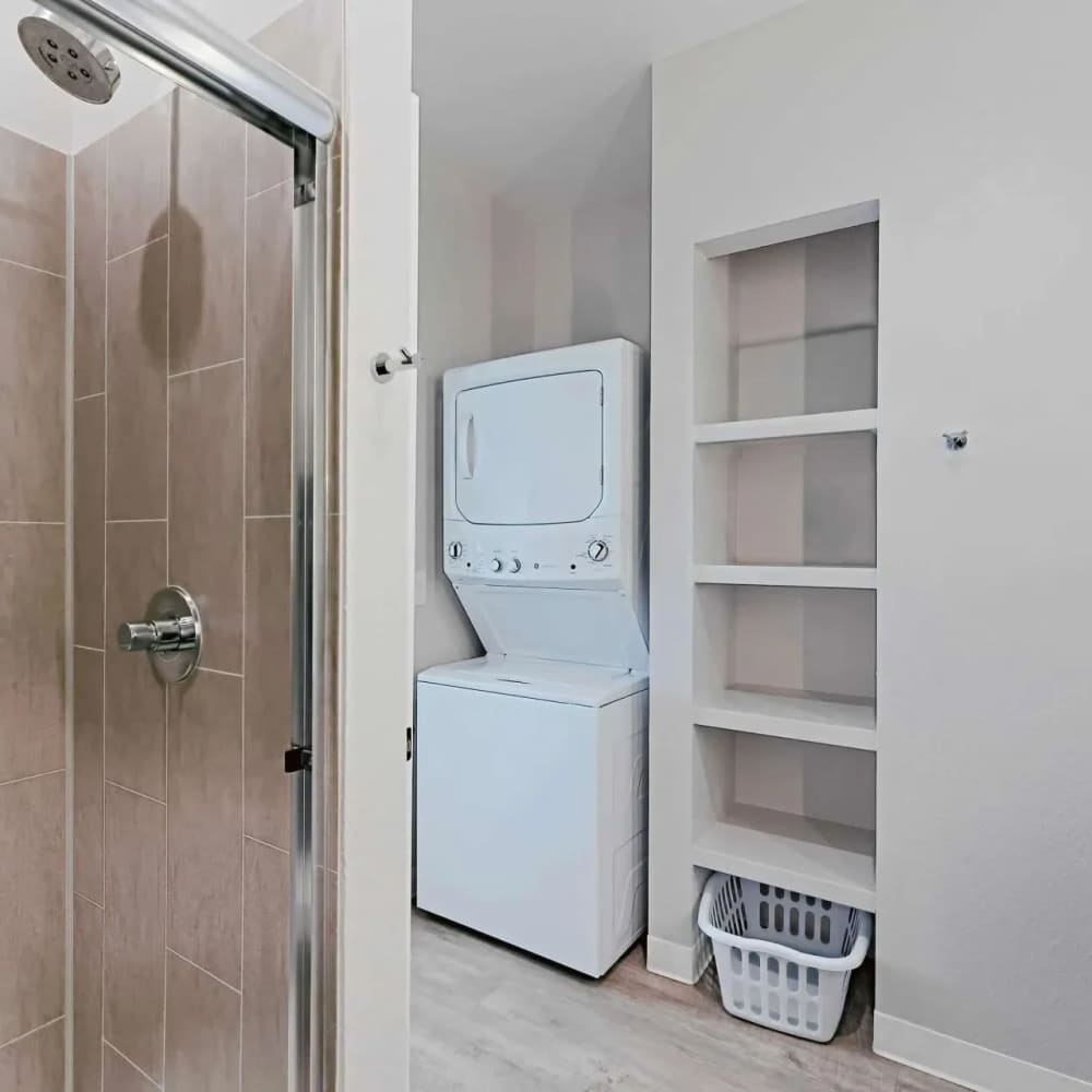 Laundry area featuring stacked washer and dryer next to a modern shower with tiled walls at WaterWalk Boise - Meridian in Meridian, Idaho
