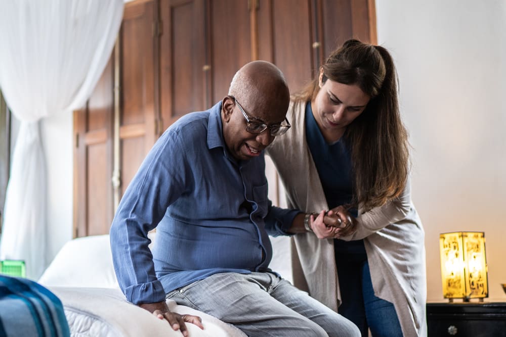 Caretaker assisting a resident out of bed at The Manor at Market Square in Reading, Pennsylvania