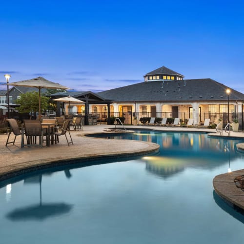 Winding resort-style swimming pool with a sun deck at Olympus Woodbridge in Sachse, Texas
