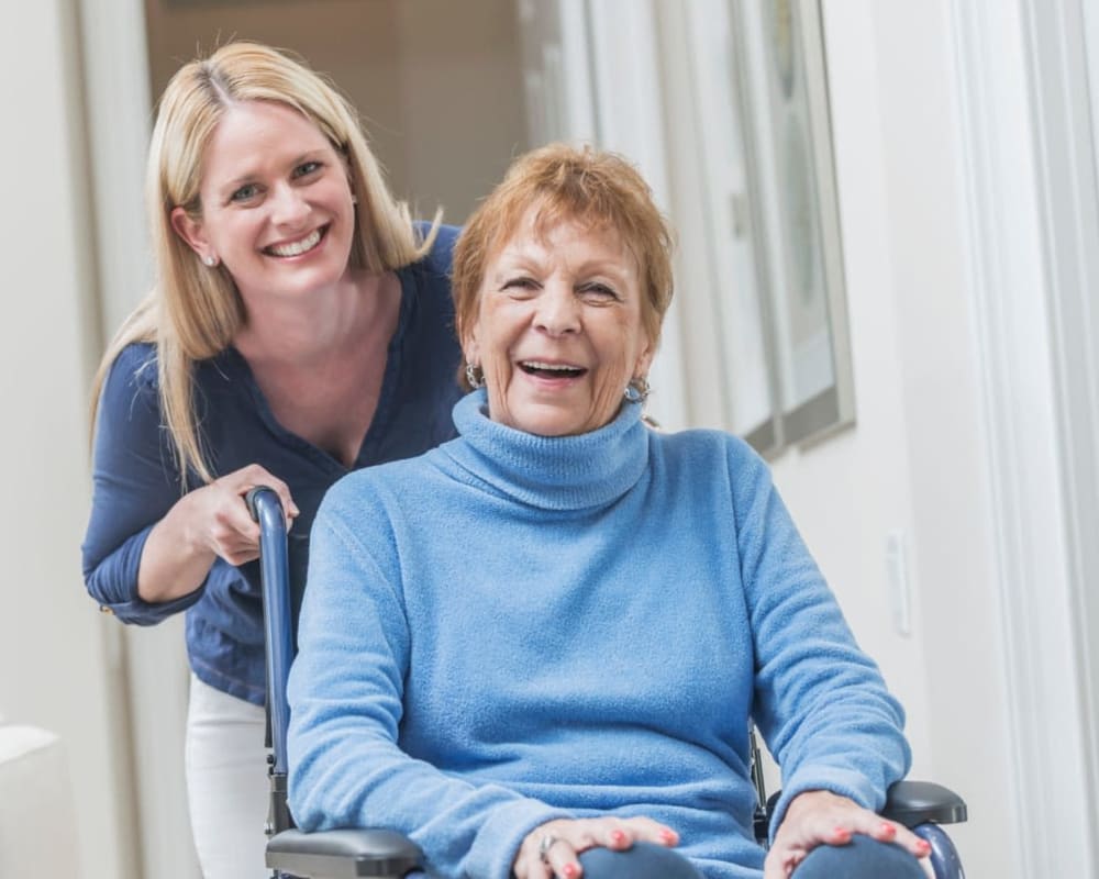 Staff member pushing a resident in a wheelchair at The Preserve of Roseville in Roseville, Minnesota. 