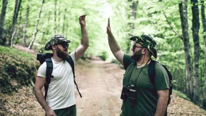 Two people hiking in the woods giving each other high five.