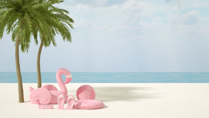 Several pink objects including an inflatable swan, beach ball, life preserver, flip flops and sunglasses on a beach with palm trees and the ocean in the background.