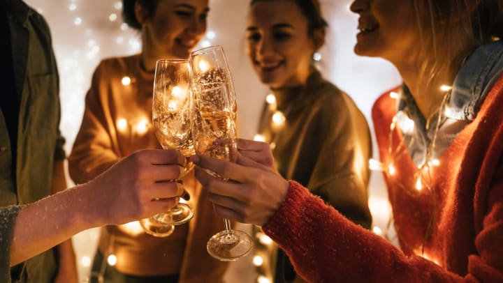 Group of people wearing lights as necklace cheers one another with Champagne glasses