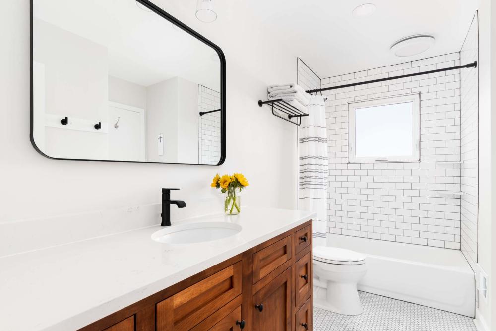 Bright bathroom with shower, tub and large mirror with sink at Athens Vista Senior Apartments in Los Angeles, California