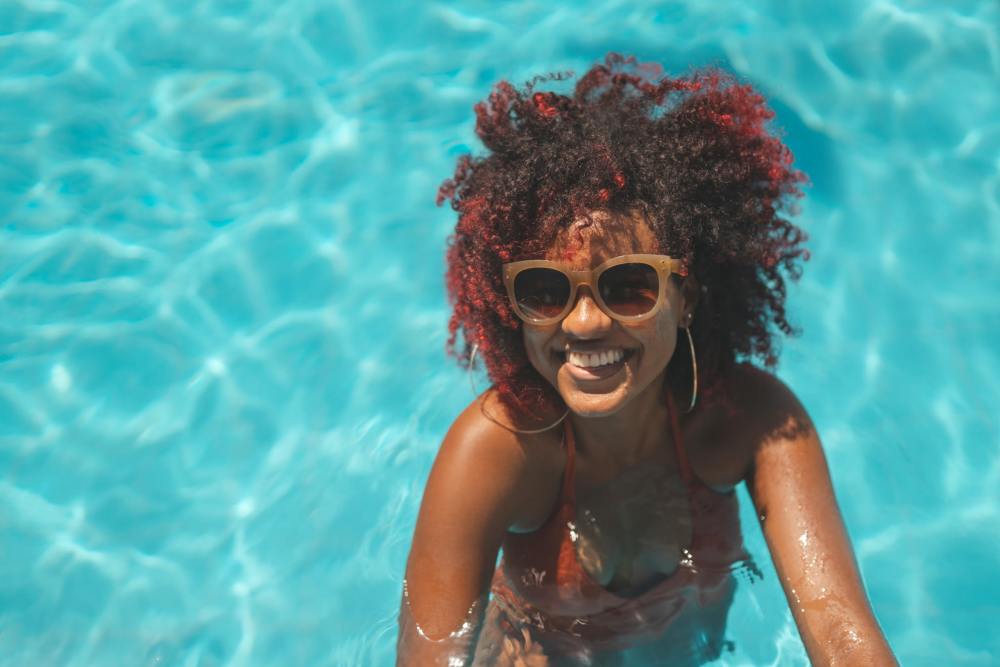 A woman with red hair and sunglasses chilling in a pool at Copper Square in Lancaster, California
