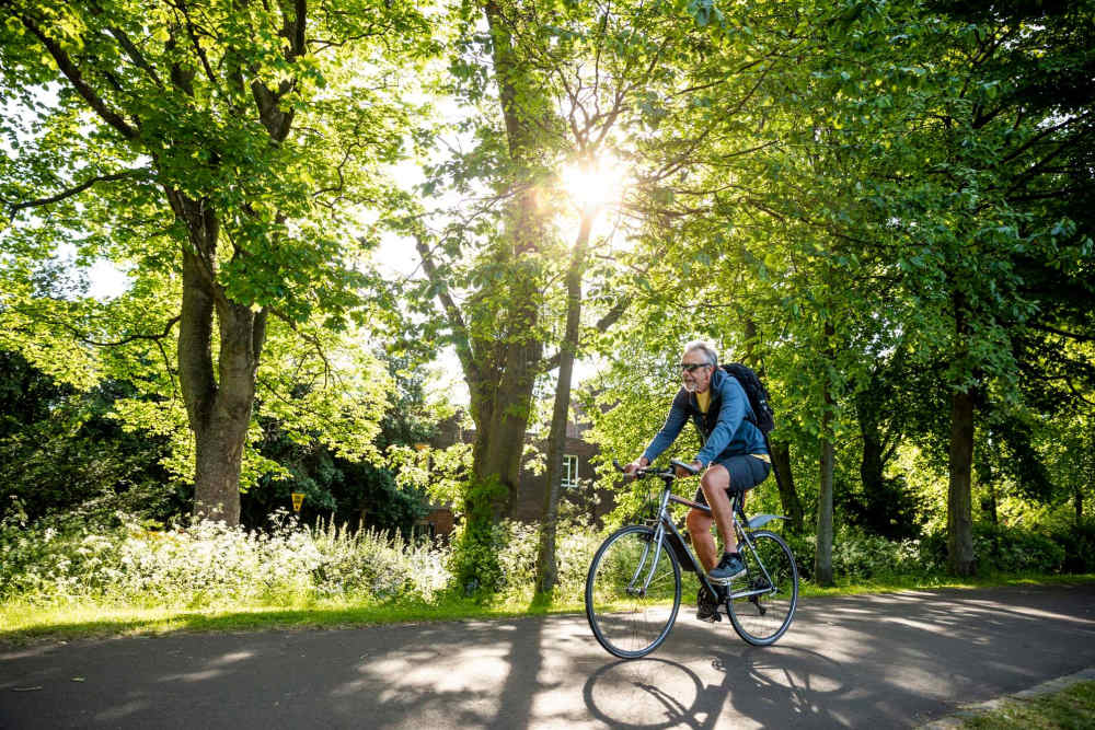 Resident cycling through a green trail at Corrigan Square Apartments in Gaithersburg, Maryland
