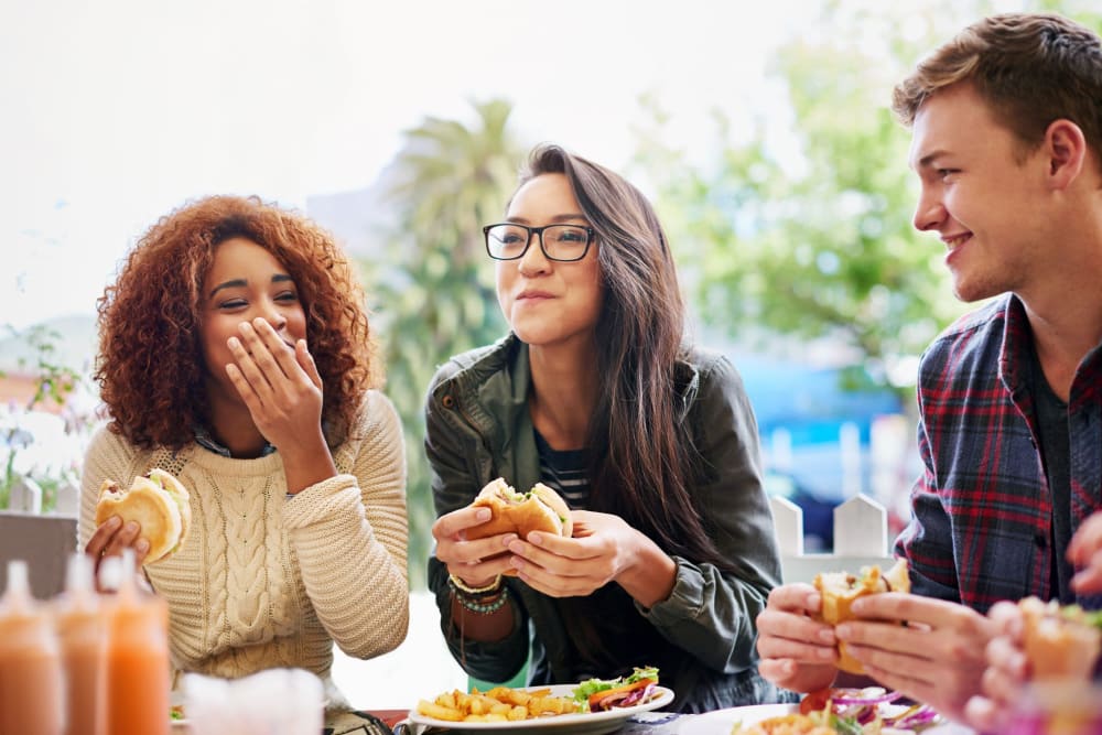 Friends laughing together having lunch at a local hot spot near Vidorra McKinney Avenue in Dallas, Texas