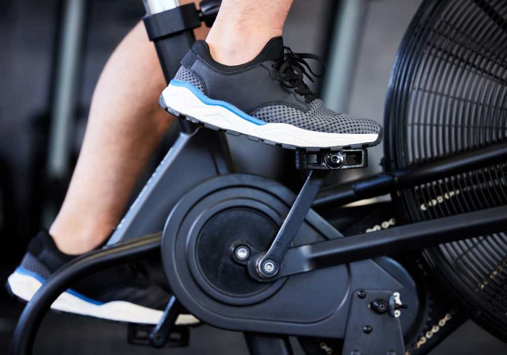 Person exercising on a stationary bike in a modern fitness center at Magnolia Crossing and Bell Ridge II in Pace, Florida