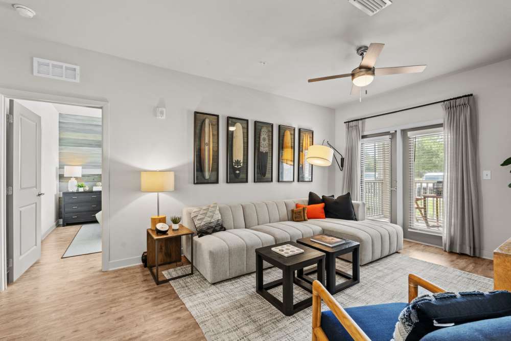 Living room with wood style flooring and large windows at Pier Park Crossings Apartments in Panama City Beach, FL.