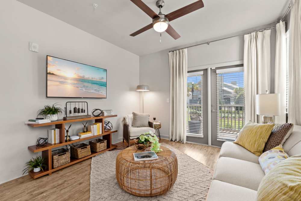 Cozy living space with wood style flooring and sun filled windows at Pier Park Crossings Apartments in Panama City Beach, Florida.