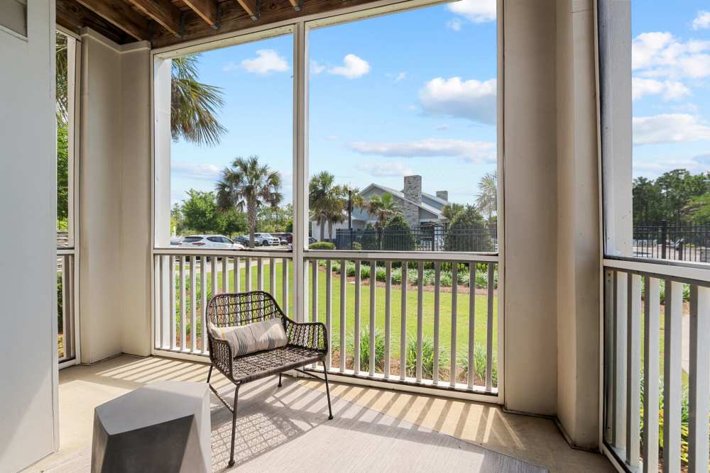Screened in patio with chair and table at Pier Park Crossings Apartments in Panama City Beach, Florida.