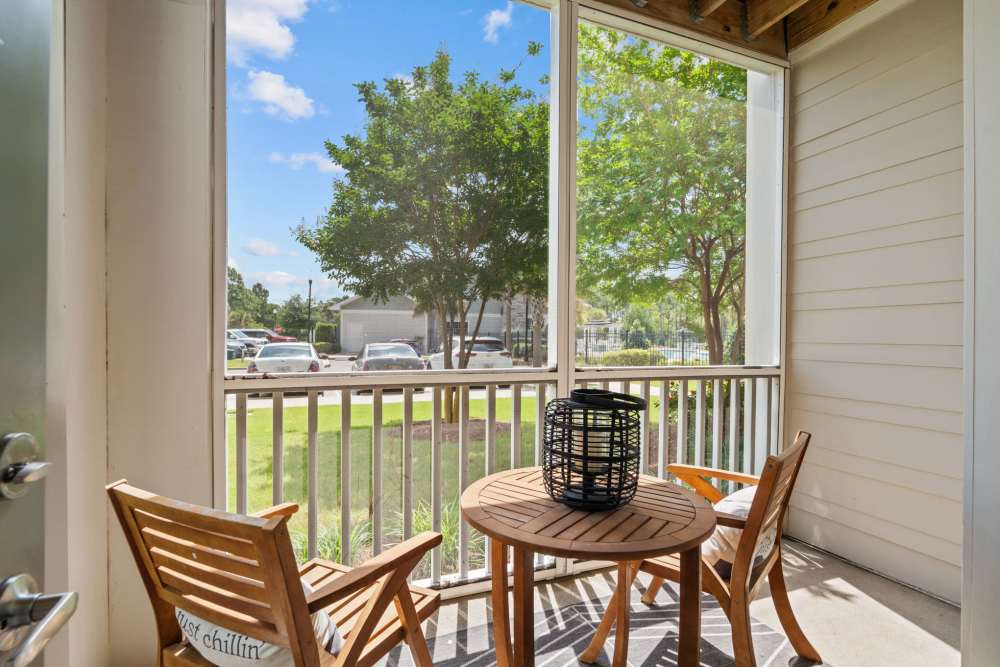 Screened in patio with two chairs and table overlooking lush landscaping at Pier Park Crossings Apartments.