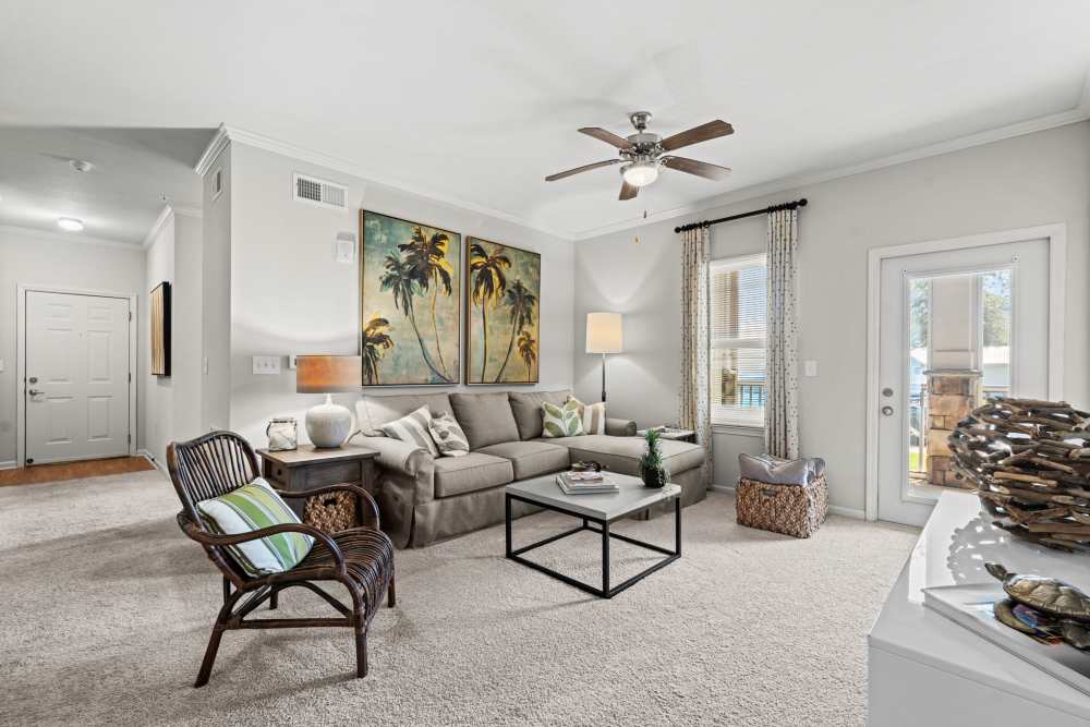 Living room with sunlight spilling in on sofa, coffee table, and carpeted flooring at The Crossings At Milestone in Pensacola, Florida