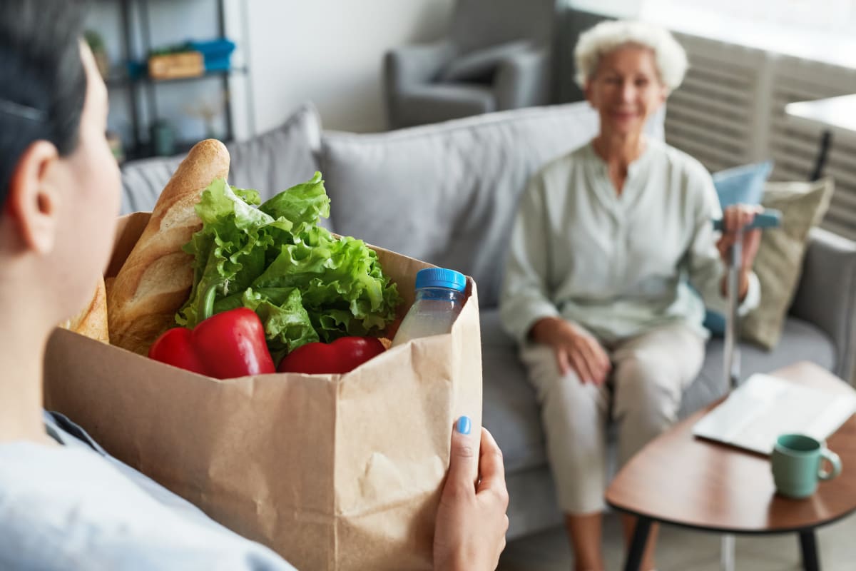Caregiver bringing resident groceries at Trustwell Living in New York, New York