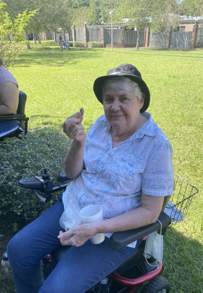 Woman with hat in outside in her wheelchair holds up a boiled peanut