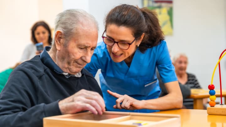 a nurse helping an older adult put a puzzle together