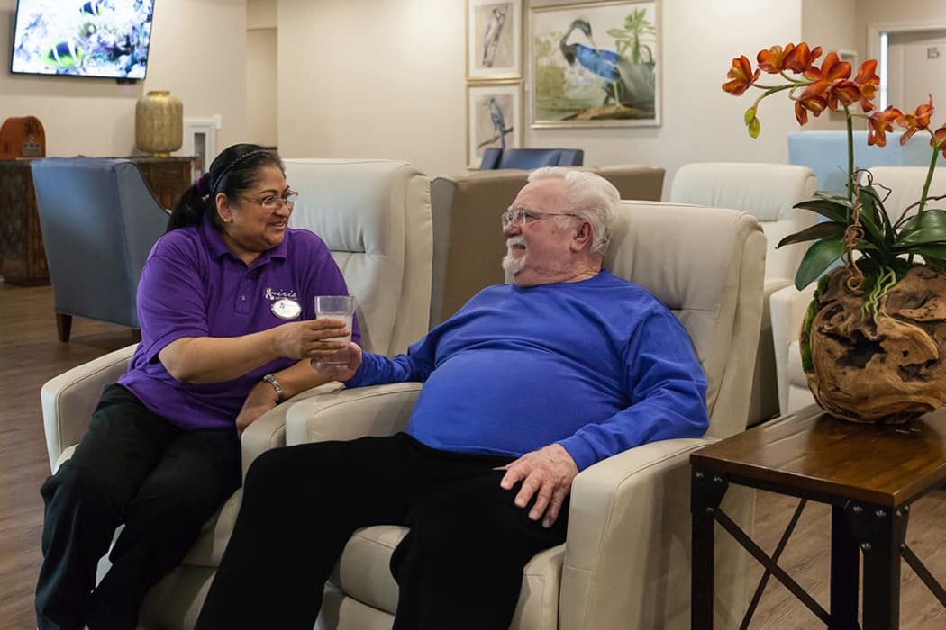 A resident and staff member getting to know each other in the Great Room at Iris Memory Care of Nichols Hills in Oklahoma City, Oklahoma. 