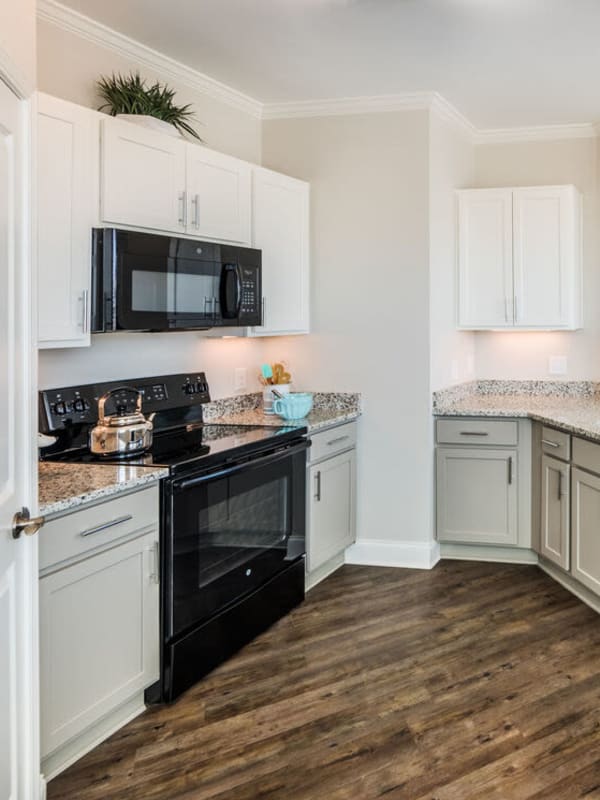 Gourmet kitchen with white cabinetry and wood-style floors at Leland Station in Leland, North Carolina