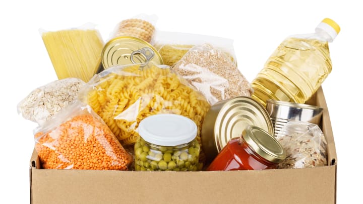 A box of various canned foods, pastas, and cereals.