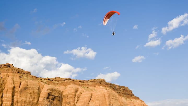 person paragliding in the sky over a desert landscape