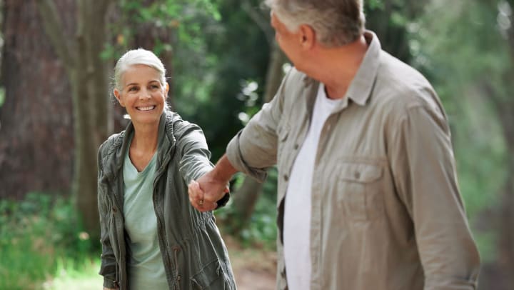 A mature couple holding hands while out hiking together.