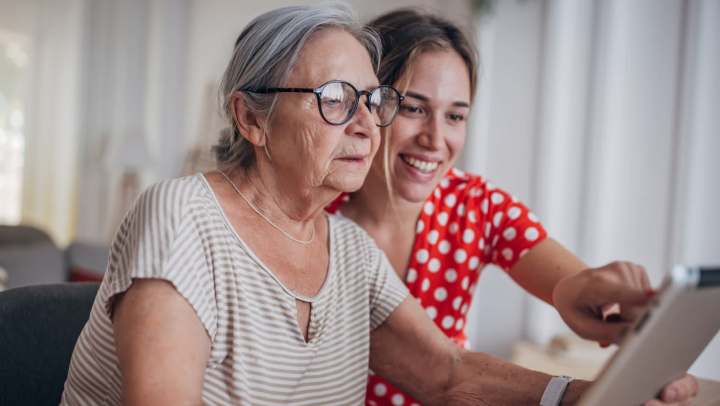 Older adult and younger person looking at a tablet together.