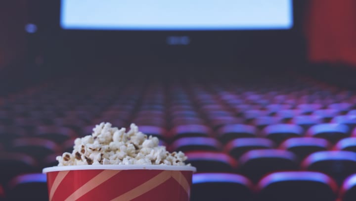 Closeup of popcorn in a bucket in an empty cinema with movie screen
