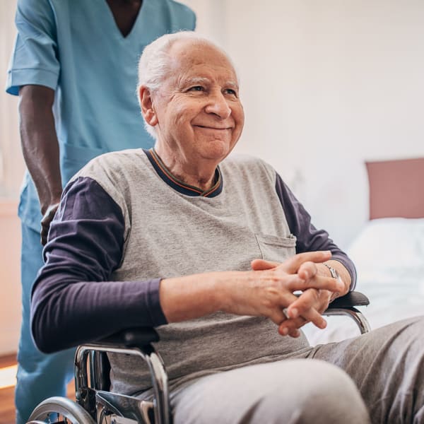Resident in wheelchair being assisted with transportation at Avila Senior Living at Downtown SLO in San Luis Obispo, California