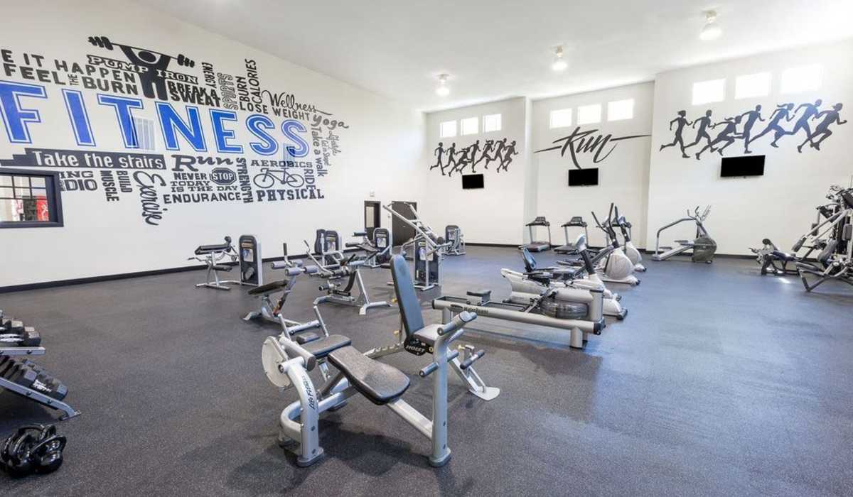Well-equipped fitness center with treadmills, weight-lifting machines and flat screen TVs at Cobblestone Park in Manvel, Texas