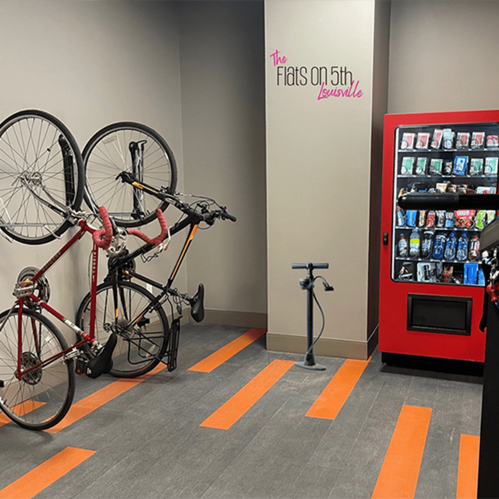 Bicycles mounted on wall with bike pump and vending machine in modern bike storage area at Flats on Fifth in Louisville, Kentucky