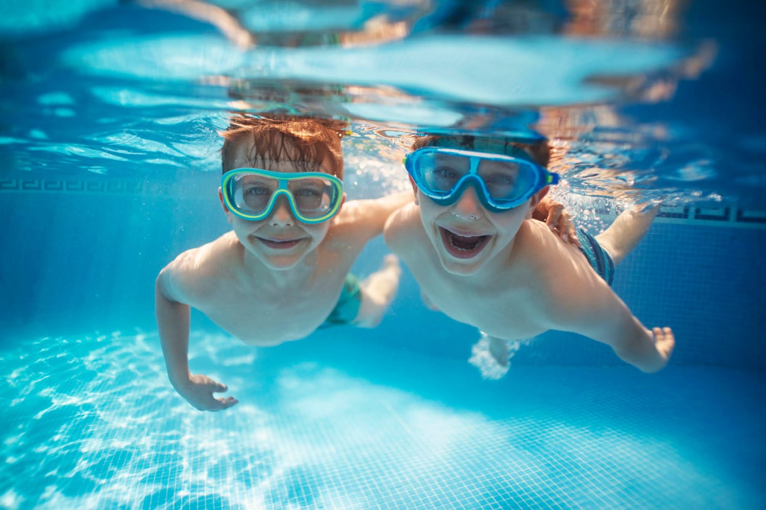 Two kids swimming in the pool with their goggles on at Waterford Place Apartments in Loveland, Colorado