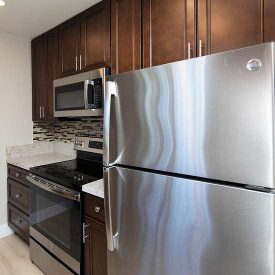 Modern kitchen with granite countertops, stainless steel appliances, and dark wood cabinetry at Villa Capri in San Diego, California 