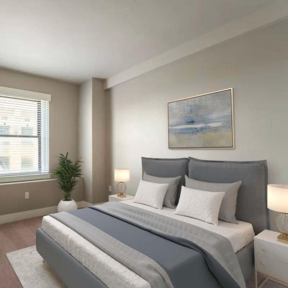 Spacious bedroom featuring a large bed, stylish lamps, and a window with natural light at Flats on Fifth in Louisville, Kentucky