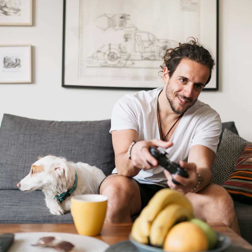 Man sitting with his dog and playing game at The Daphne in Houston, Texas